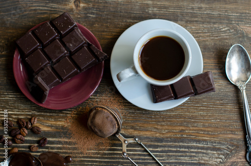 cup of coffee with a piece of chocolate on a wooden background