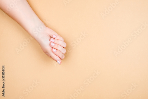 Gentle female manicure on a well-groomed hand. A woman s hand on a beige background.