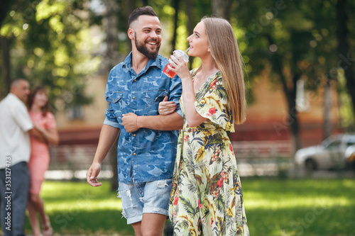 Beautiful young couple in love walking in the summer park with cold lemonade. Romantic couple on a date in the fresh air