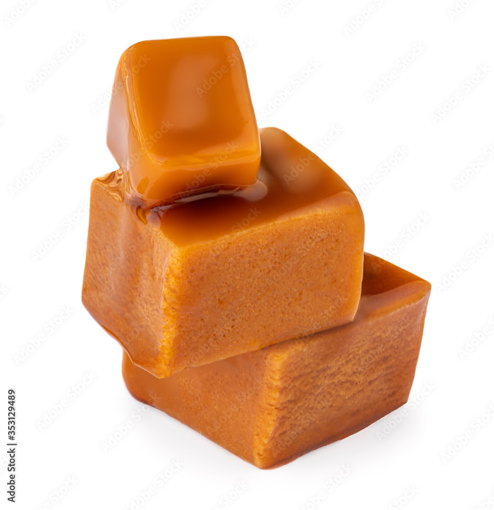 Caramel sauce flowing on caramel candies, isolated on white background. Golden Butterscotch toffee candy. Caramel sauce flowing on caramel candies, isolated on white background. Golden Butterscotch toffee candy.