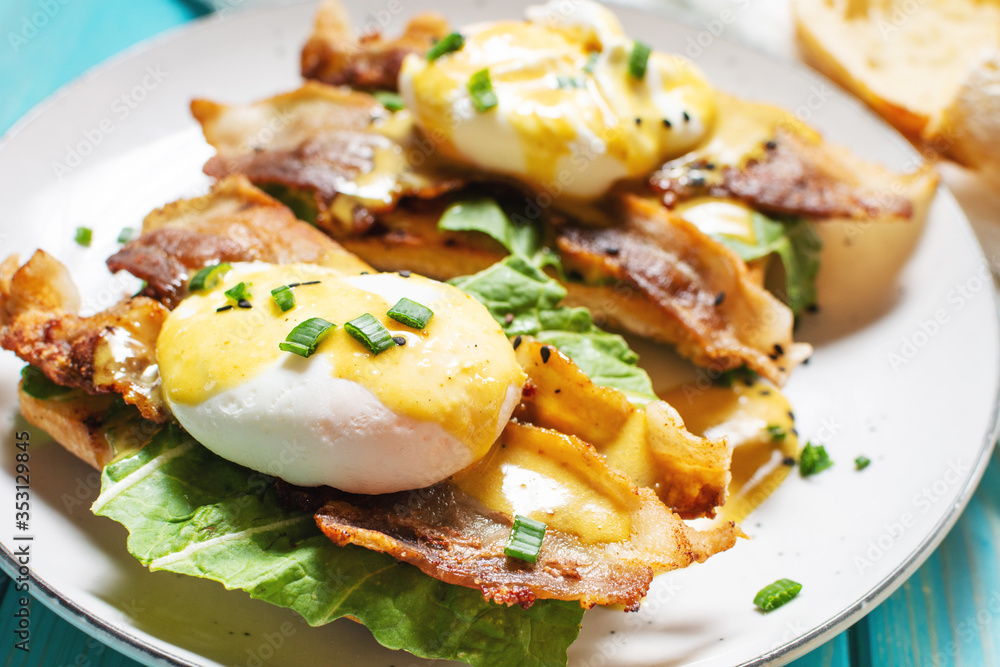 Sandwich with Eggs Benedict, bacon and salad on blue wooden background. Sandwich with Eggs Benedict, bacon and salad on blue wooden background.