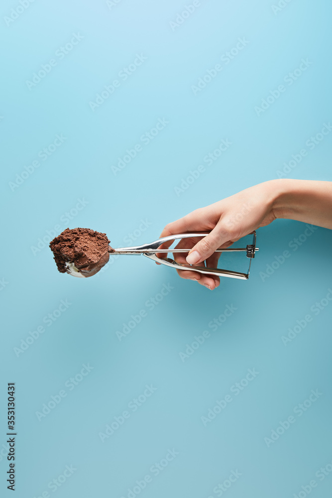 cropped view of woman holding scoop with chocolate ice cream on blue background cropped view of woman holding scoop with chocolate ice cream on blue background