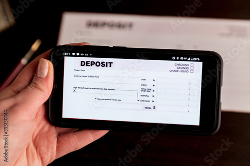 Man Taking Photo Of Cheque To Make Remote Deposit In bank