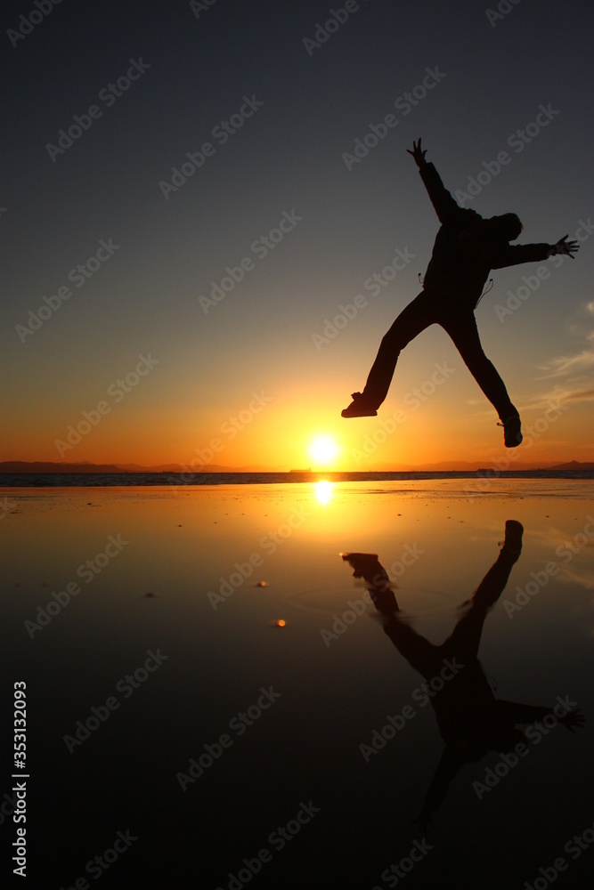 A silhouette of a man jumping over a pit filled with water
