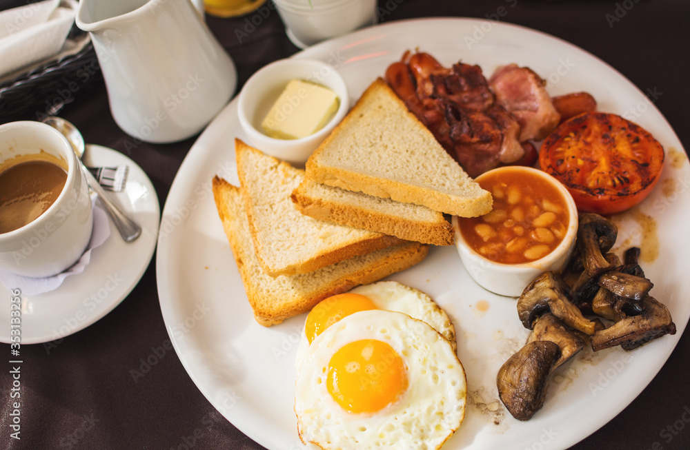 Traditional full English breakfast with fried eggs, bacon, sausages, beans in tomato sauce, toast, fried tomatoes and mushrooms Traditional full English breakfast with fried eggs, bacon, sausages, beans in tomato sauce, toast, fried tomatoes and mushrooms