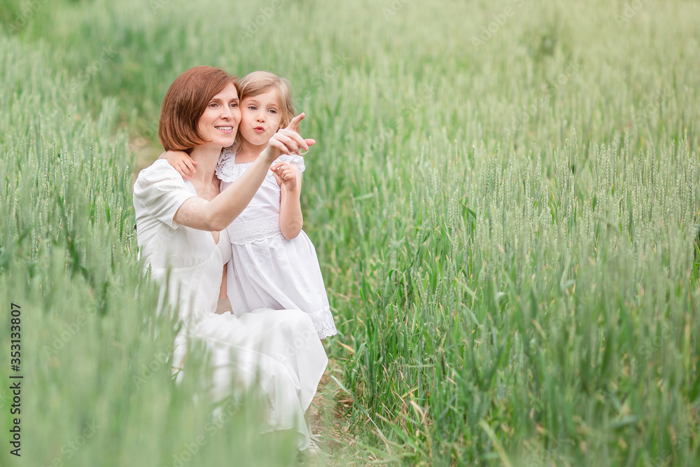Mother and daughter walking in the field. A blonde girl with long hair gives her mother a bouquet of poppies for mother's day. Mother and daughter walking in the field. A blonde girl with long hair gives her mother a bouquet of poppies for mother's day.