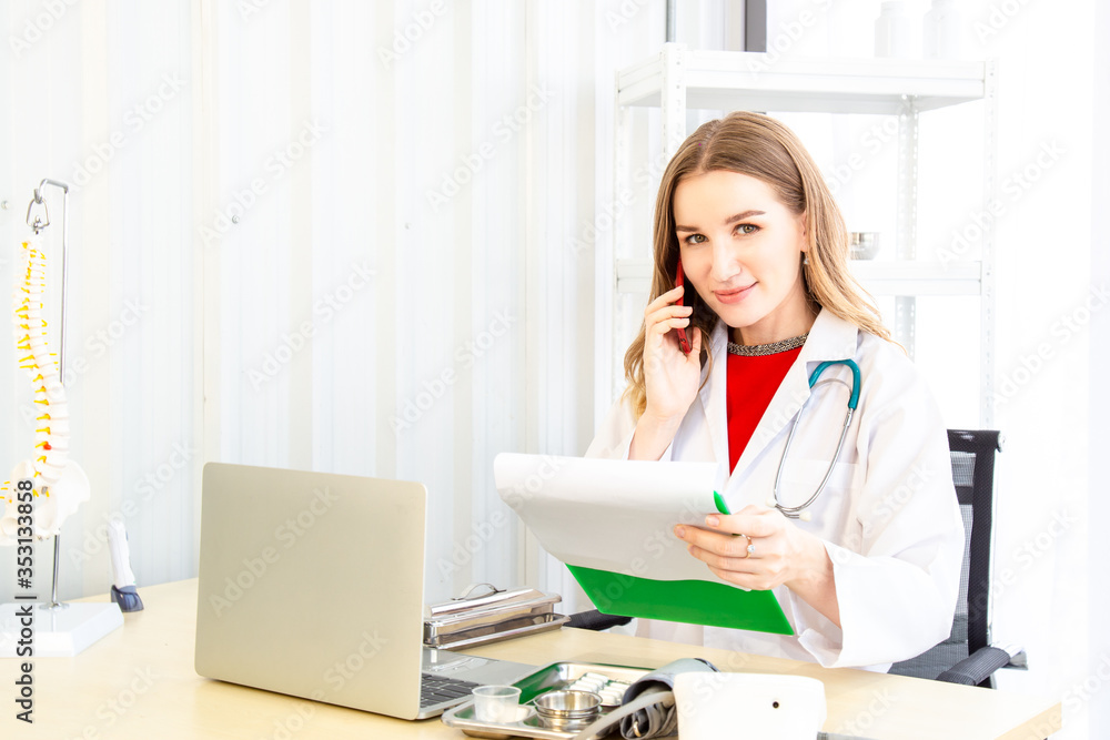 Female beautiful wearing a doctor uniform holding a green paper chart and talking on mobile phone. Female beautiful wearing a doctor uniform holding a green paper chart and talking on mobile phone.