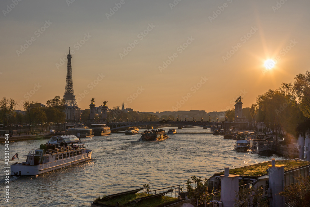sunset over seine river in Paris with Eiffel tower, Pont Alexandre III bridge, and cruise boats