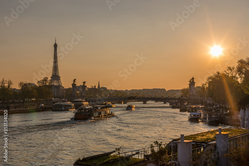 sunset over seine river in Paris with Eiffel tower, Pont Alexandre III bridge,  and cruise boats