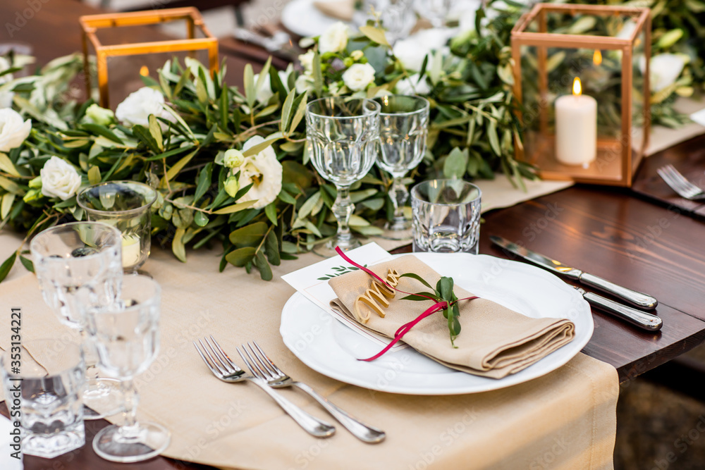 in backyard of villa in Tuscany there is banquet wooden table decorated with cotton and eucalyptus compositions, glasses, candles and plates are placed on table in backyard of villa in Tuscany there is banquet wooden table decorated with cotton and eucalyptus compositions, glasses, candles and plates are placed on table