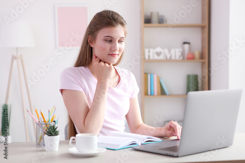 The girl works remotely from home using a modern laptop. 