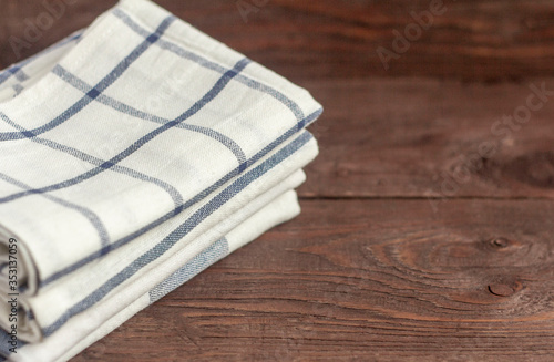 A stack of kitchen towels are stacked on an old rustic table.