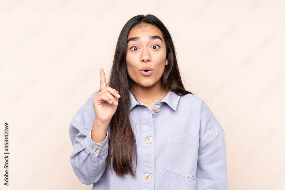 Young Indian woman isolated on beige background intending to realizes the solution while lifting a finger up