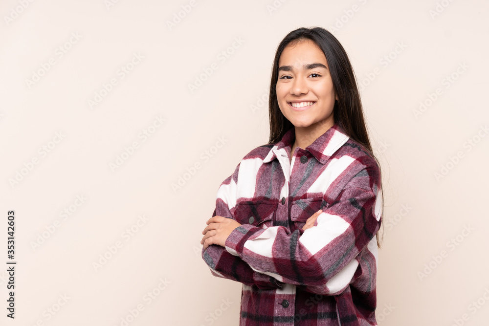 Young Indian woman isolated on beige background with arms crossed and looking forward Young Indian woman isolated on beige background with arms crossed and looking forward