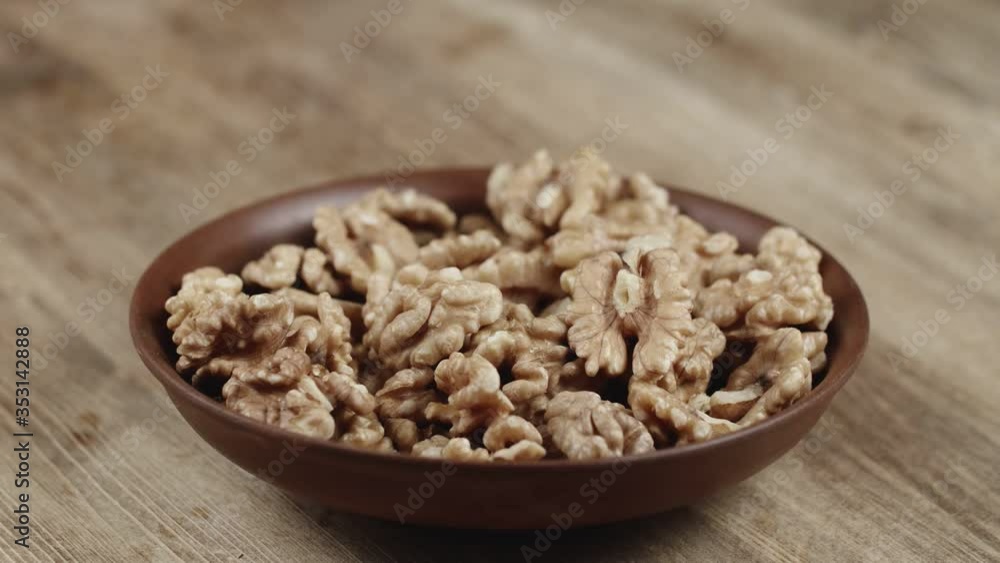 Woman Picks Up A Single walnut, To Eat, From Her Bowl. took a nut on the right side Woman Picks Up A Single walnut, To Eat, From Her Bowl. took a nut on the right side