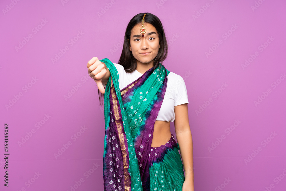 Young Indian woman with sari over isolated background showing thumb down with negative expression Young Indian woman with sari over isolated background showing thumb down with negative expression