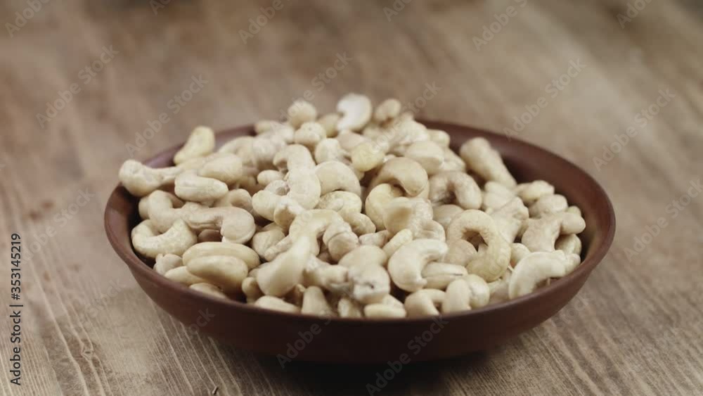 Woman Picks Up A Single Cashew, To Eat, From Her Bowl. took a nut on the right side Woman Picks Up A Single Cashew, To Eat, From Her Bowl. took a nut on the right side