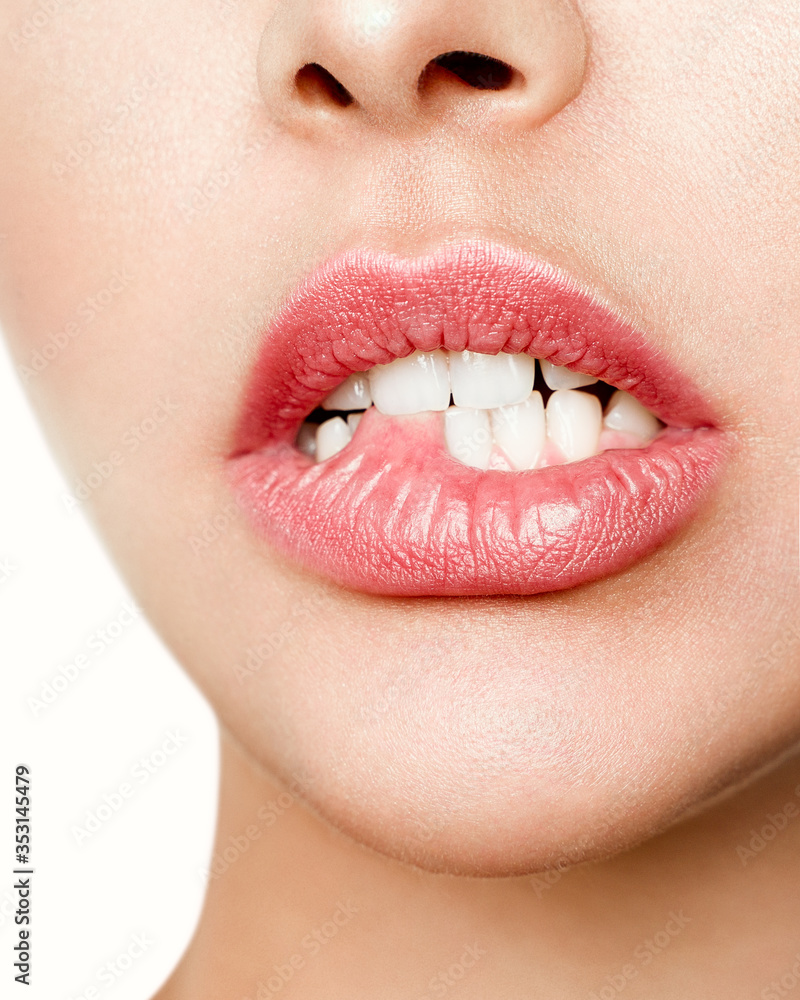 Obraz premium Close-up of the white teeth of a woman biting her lips