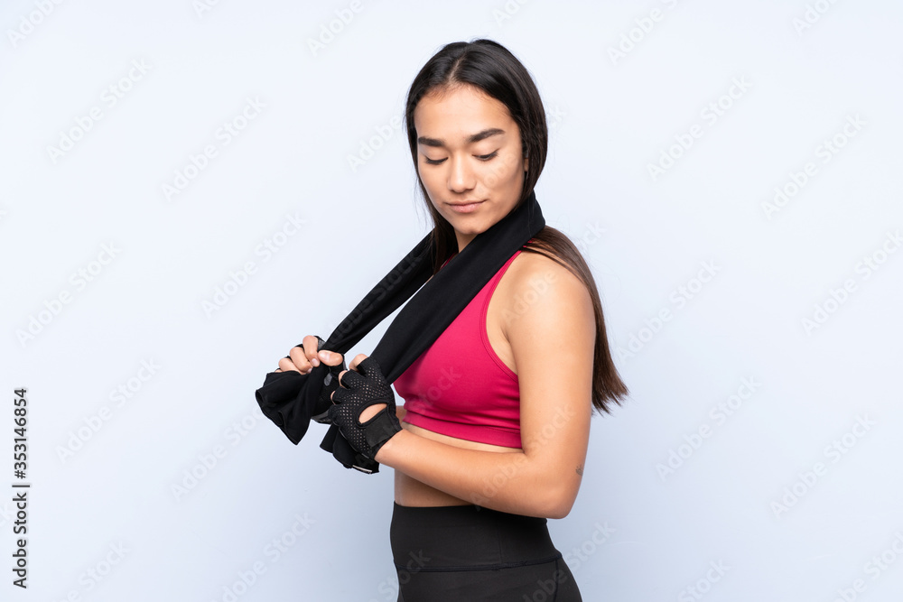 Young Indian sport woman isolated on blue background with sport towel Young Indian sport woman isolated on blue background with sport towel