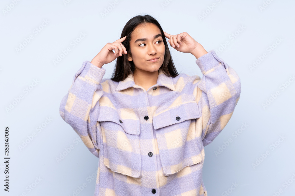 Young Indian woman isolated on blue background having doubts and thinking Young Indian woman isolated on blue background having doubts and thinking