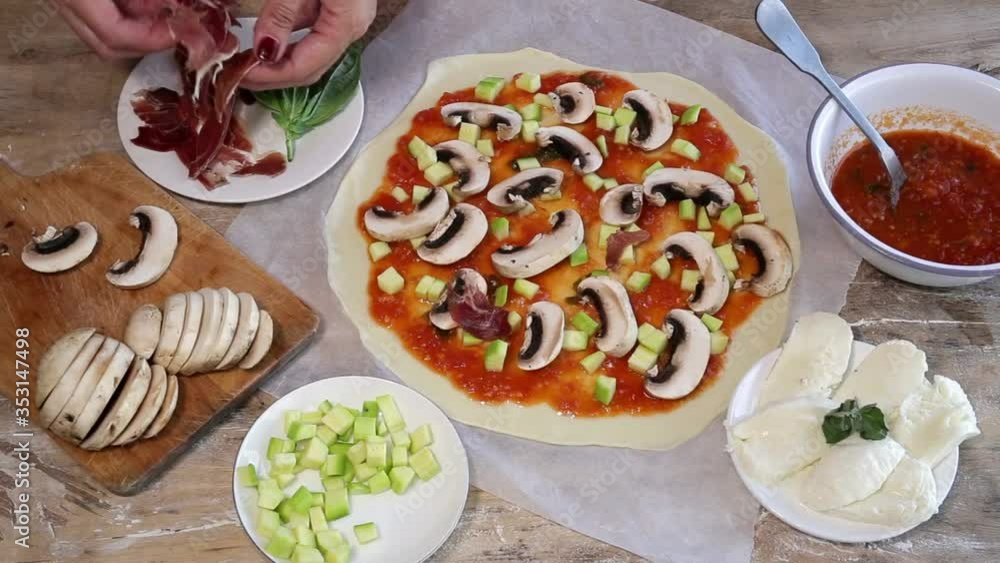 Cook hands making pizza dough and preparing with tomato, mushrooms, ham, mozzarella and parmesan cheese. Cook hands making pizza dough and preparing with tomato, mushrooms, ham, mozzarella and parmesan cheese.