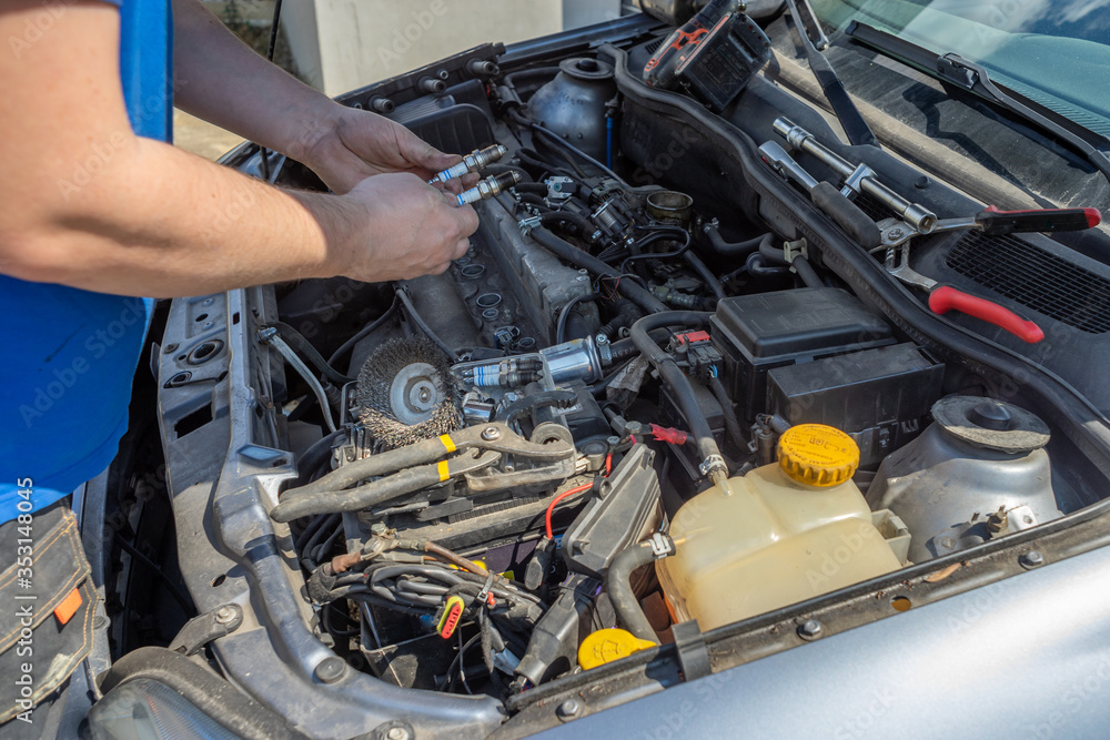 The person changes candles in the car, checks which is good The person changes candles in the car, checks which is good