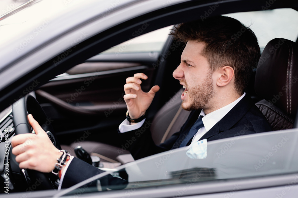 Angry businessman driving alone in his new car