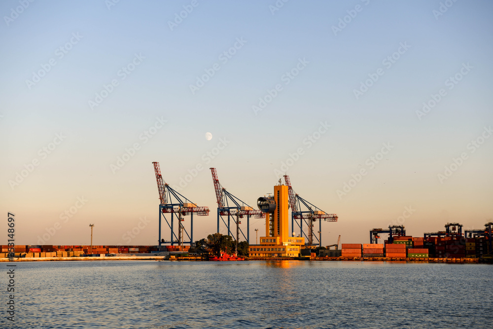 The cranes in the port of Odessa at sunset with the moon in the background.