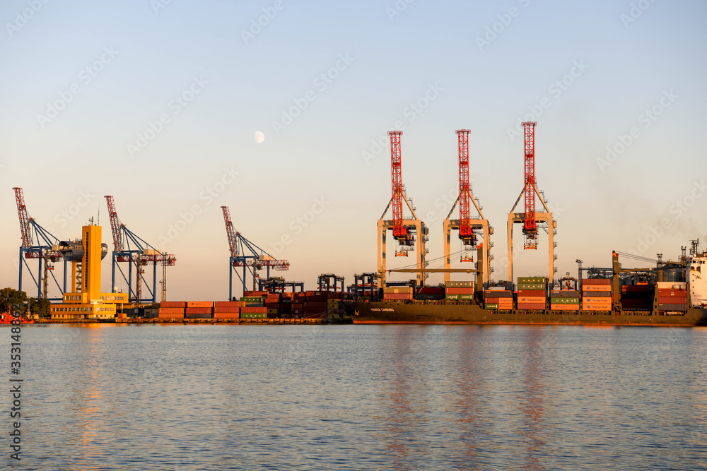 The cranes in the port of Odessa at sunset with the moon in the background.