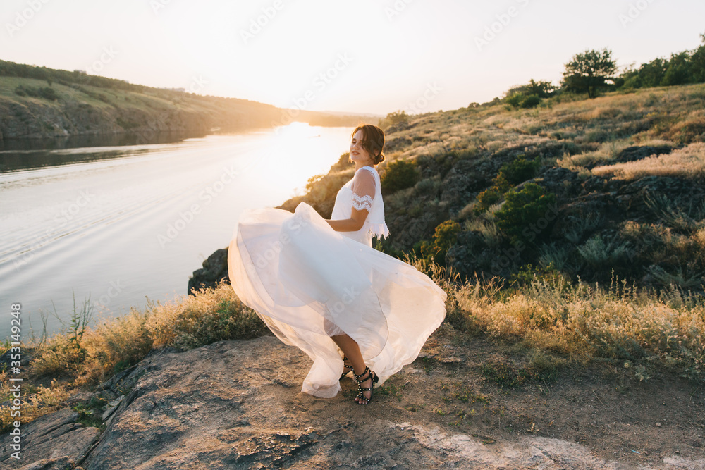 Bride in a luxurious white wedding dress in nature at sunset