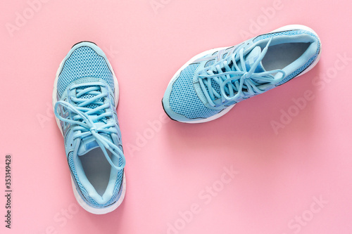 Blue sneakers isolated on a pink background, seasonal shoes for walking and sports, copy space, top view