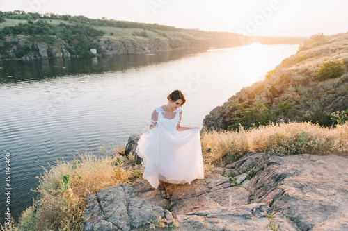 Bride in a luxurious white wedding dress in nature at sunset