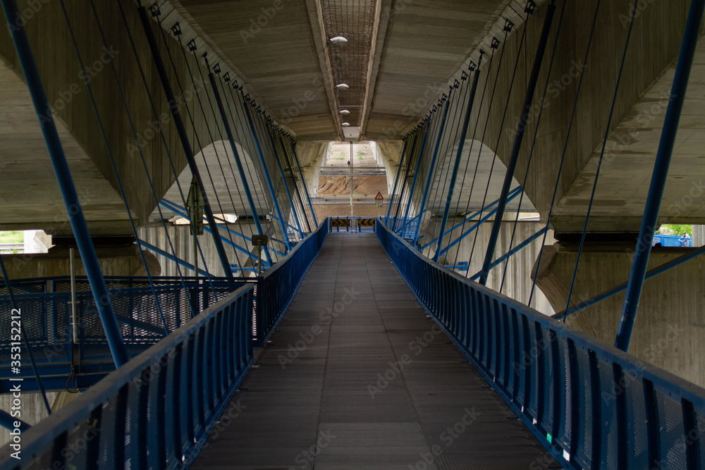 blue footbridge under the cement bridge on which is a road for cars in the city of Prague in the spring
blue footbridge under the cement bridge on which is a road for cars in the city of Prague in the spring
