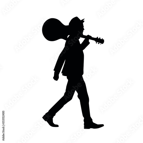 Silhouette of man walking with guitar on his shoulder