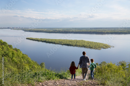 mom and two kids walk near the river. Social Distancing. end of a quarantine. Staycations, hyper-local travel, family outing, getaway, natural environ