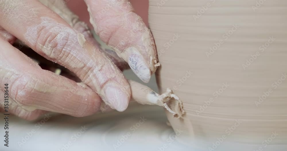 Female potter sitting and makes a cup on the pottery wheel. Woman making ceramic item. Pottery working, handmade and creative skills Female potter sitting and makes a cup on the pottery wheel. Woman making ceramic item. Pottery working, handmade and creative skills