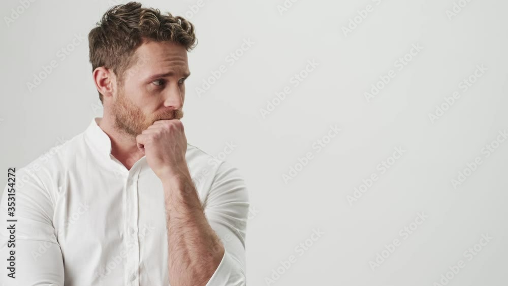 Handsome young serious man in white shirt isolated over white wall background Handsome young serious man in white shirt isolated over white wall background