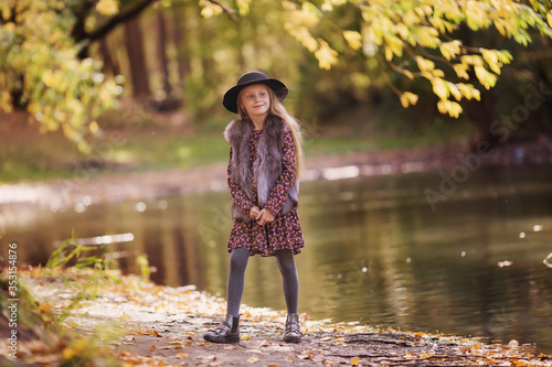 Portrait of a beautiful smiling fashionable girls. Little girl with long hair standing by the pond on a sunny day