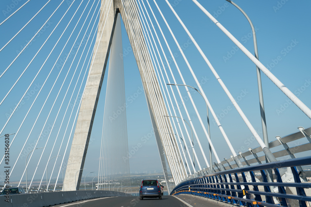 view of the bridge across the strait soars its pylons and a car rides into the distance