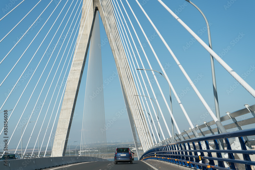 view of the bridge across the strait soars its pylons and a car rides into the distance view of the bridge across the strait soars its pylons and a car rides into the distance
