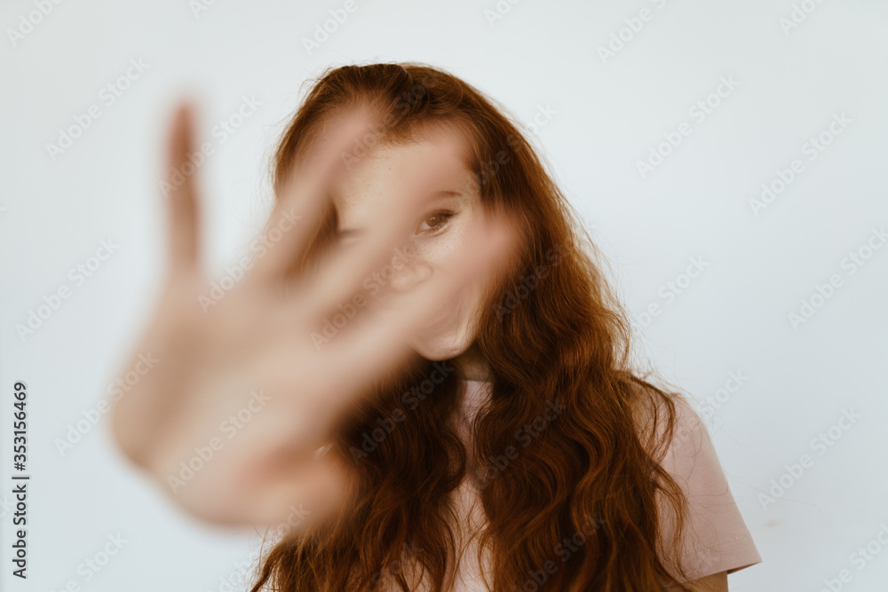 cheerfully smiling red-haired disheveled girl closes the camera with a palm with spread fingers cheerfully smiling red-haired disheveled girl closes the camera with a palm with spread fingers