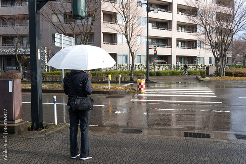 A woman and white umbrella waiting signal  for cross walk.