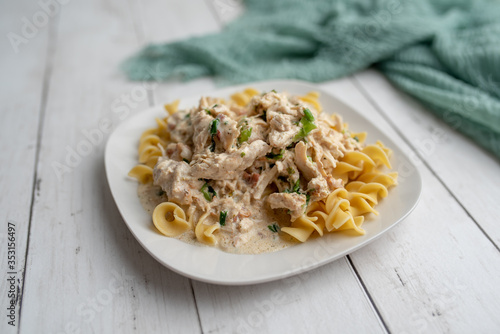 Fotografie Crack chicken slow cooked dish over egg  pasta on a white plate