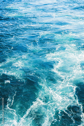 Sea or ocean waves surface texture. Abstract summer blue water background with splashes of sea foam. © tumana_net