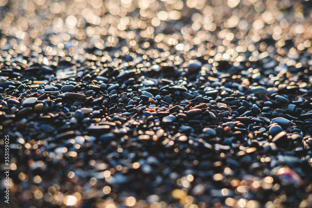 Small stones by the sea with bokeh effect. Blurred decorative background, place for text. Summer wallpaper, sunny sunset light. Small stones by the sea with bokeh effect. Blurred decorative background, place for text. Summer wallpaper, sunny sunset light.