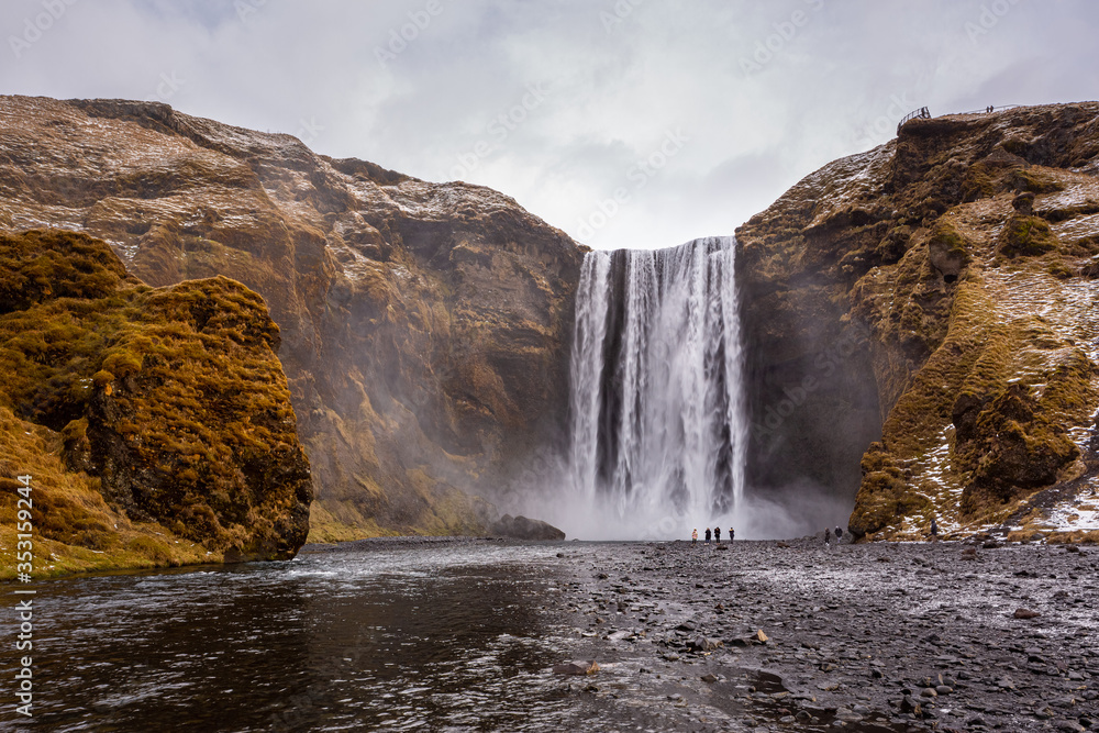 Skogafoss waterfall in South Iceland. Tourists admiring the waterfall. Popular and famous tourist attraction. Skogafoss waterfall in South Iceland. Tourists admiring the waterfall. Popular and famous tourist attraction.