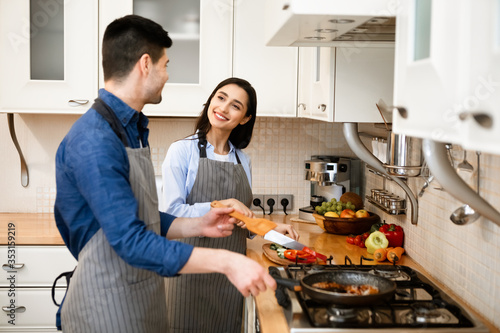 Loving couple preparing dinner frying on pan at home
