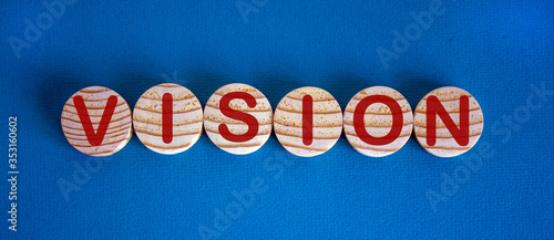 The word 'vision' on wooden circles on blue table. Beautiful background, copy space.