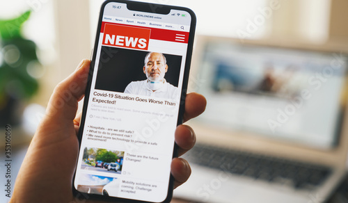 Obraz na płótnie Close up of businessman reading news or articles in a mobile phone screen app. Hand holding smart device. Mockup website. Newspaper and portal on internet. Displayed news are not reality related. w salonie