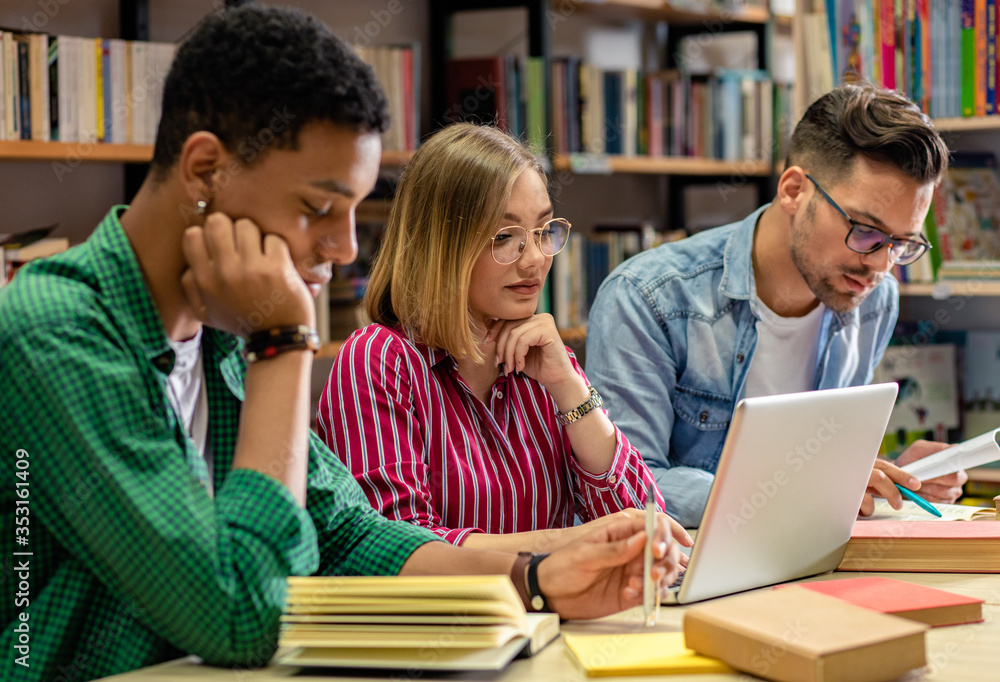 Portrait of young african american student sitting in library studying, with his friends in background. Portrait of young african american student sitting in library studying, with his friends in background.